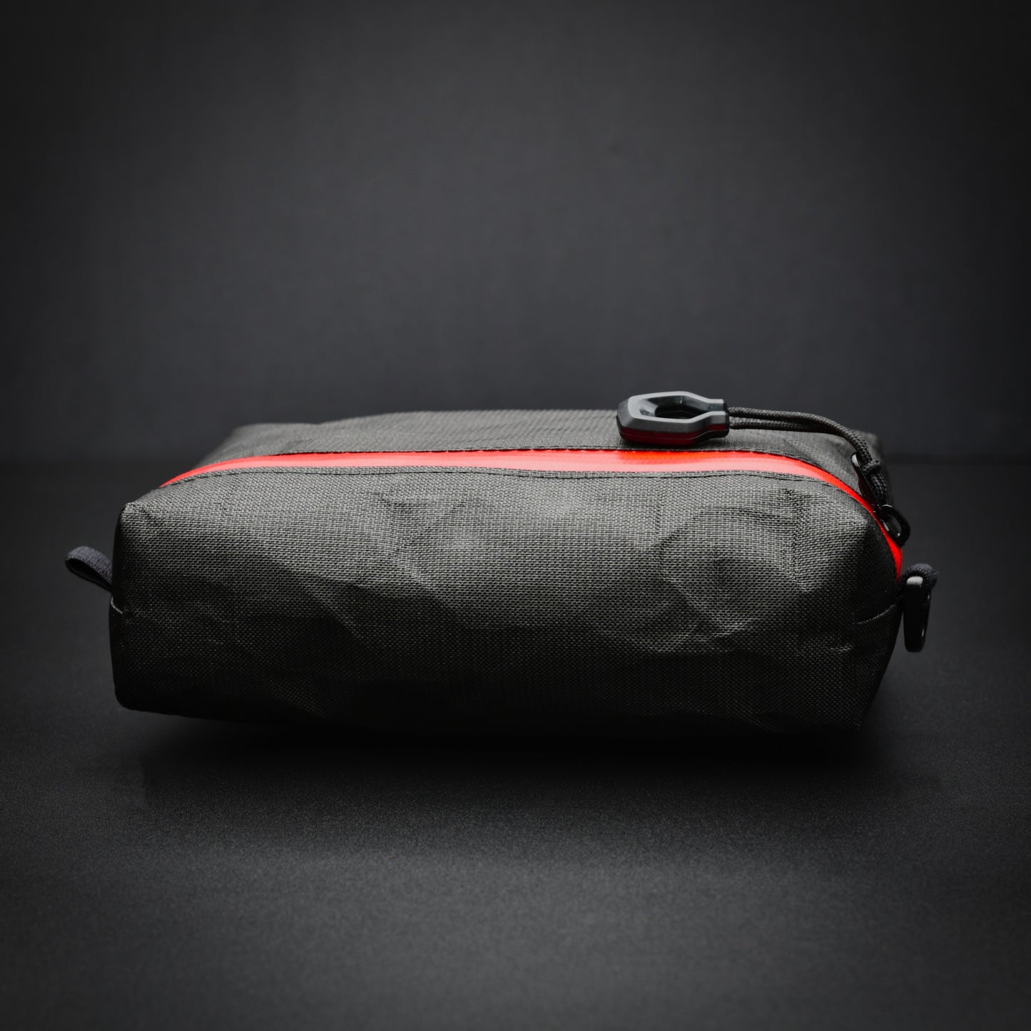 Side profile of a black EcoPak Ultra™ accessory pouch showing the boxed base and red YKK® AquaGuard® zip.