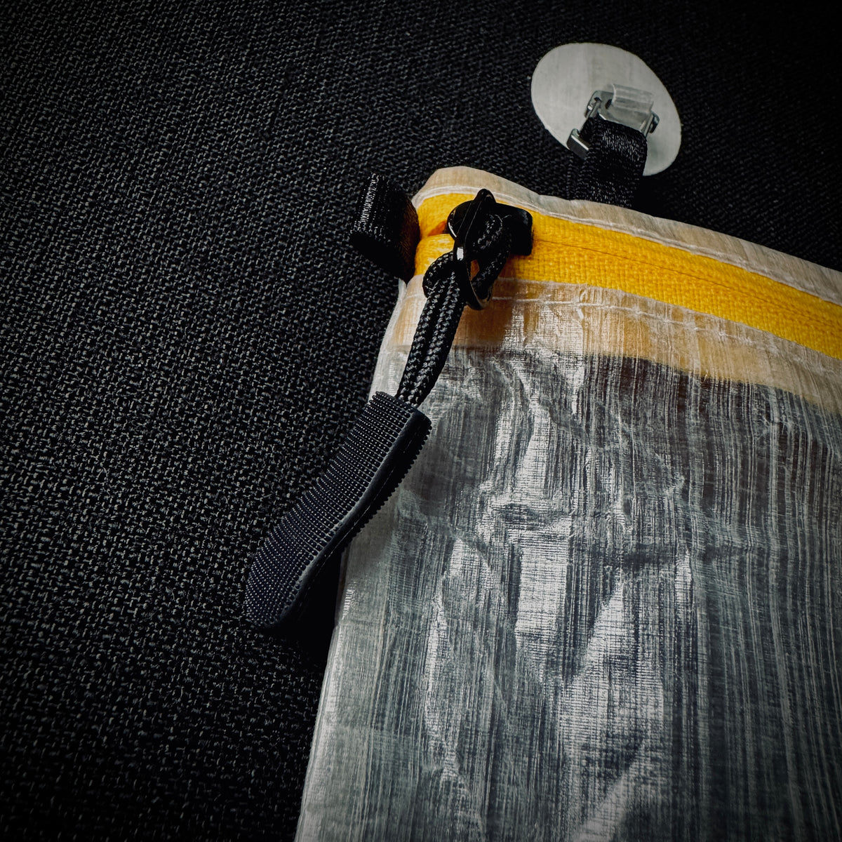 Close-up of the pouch’s yellow zip and black pull, with a Microdot attached to the top tab.