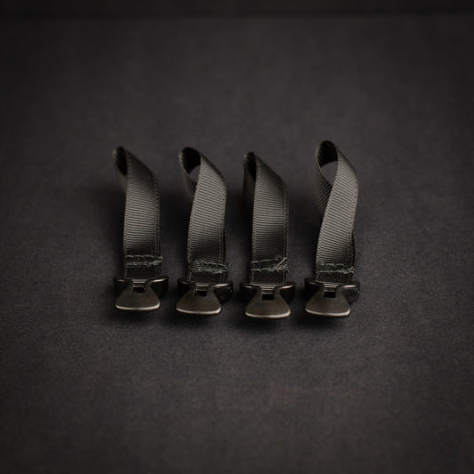 Four black LineLoc 3 self-tensioning tarp adjusters pre-fitted to black grosgrain loops for ultralight shelter and guyline systems.