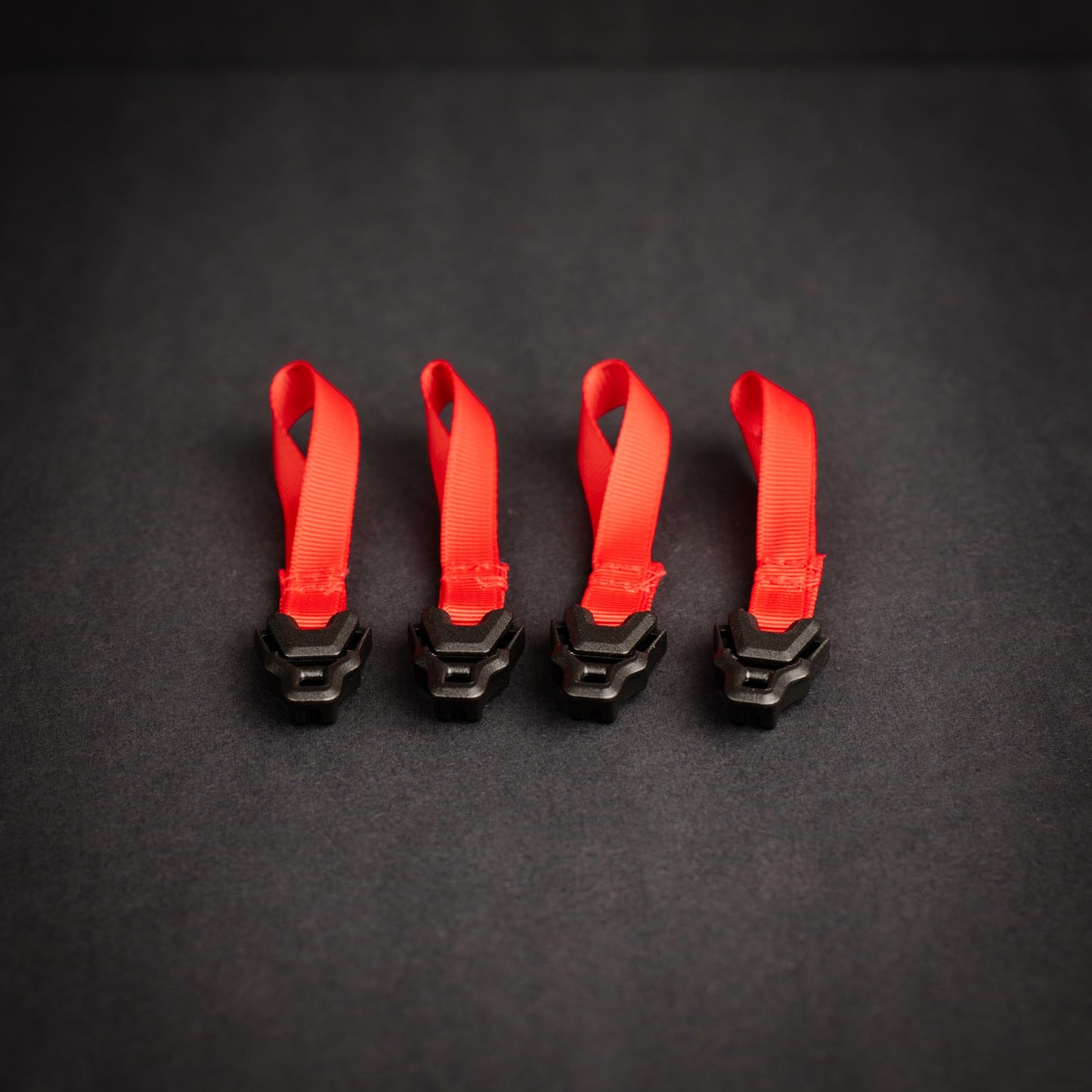 Four Z Buckle tensioners fitted to high-visibility red grosgrain loops for tarp, tent and shelter guyline adjustment