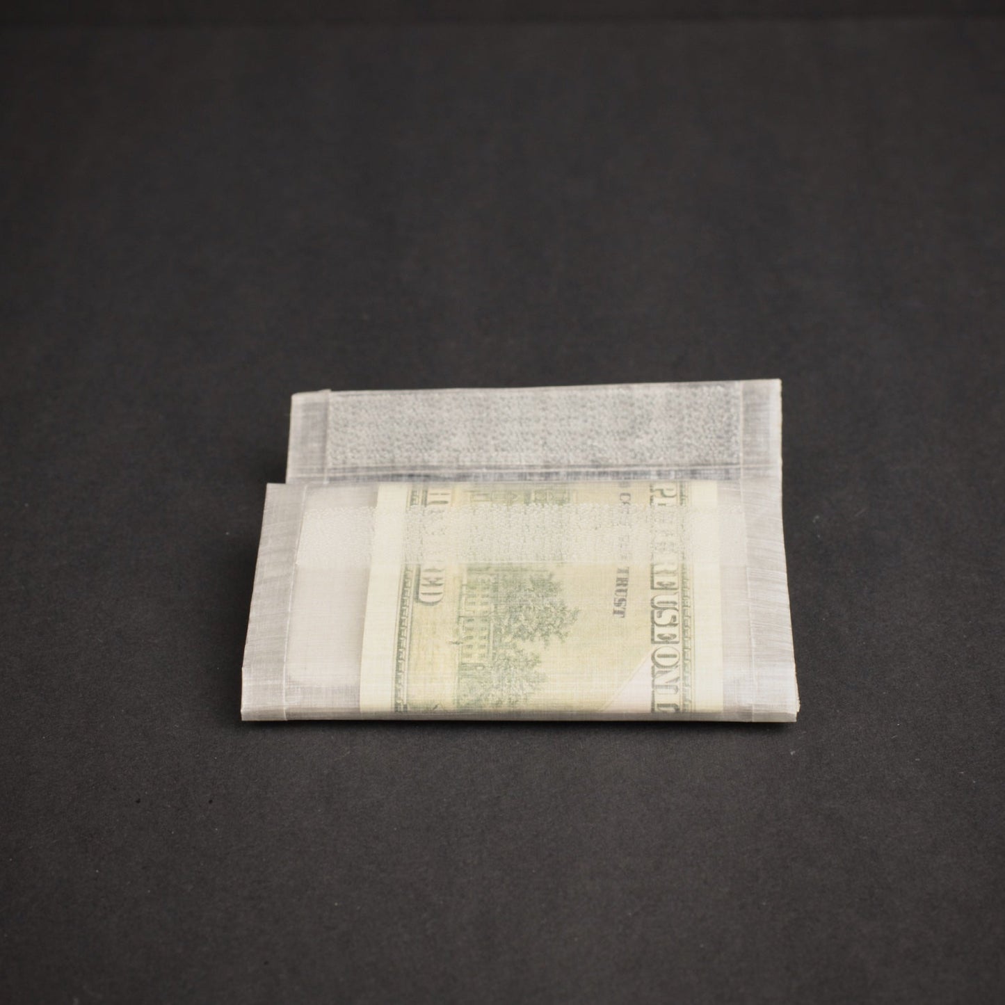 Folded ultralight Dyneema wallet holding cash, showing the slim profile and lightweight bonded construction.