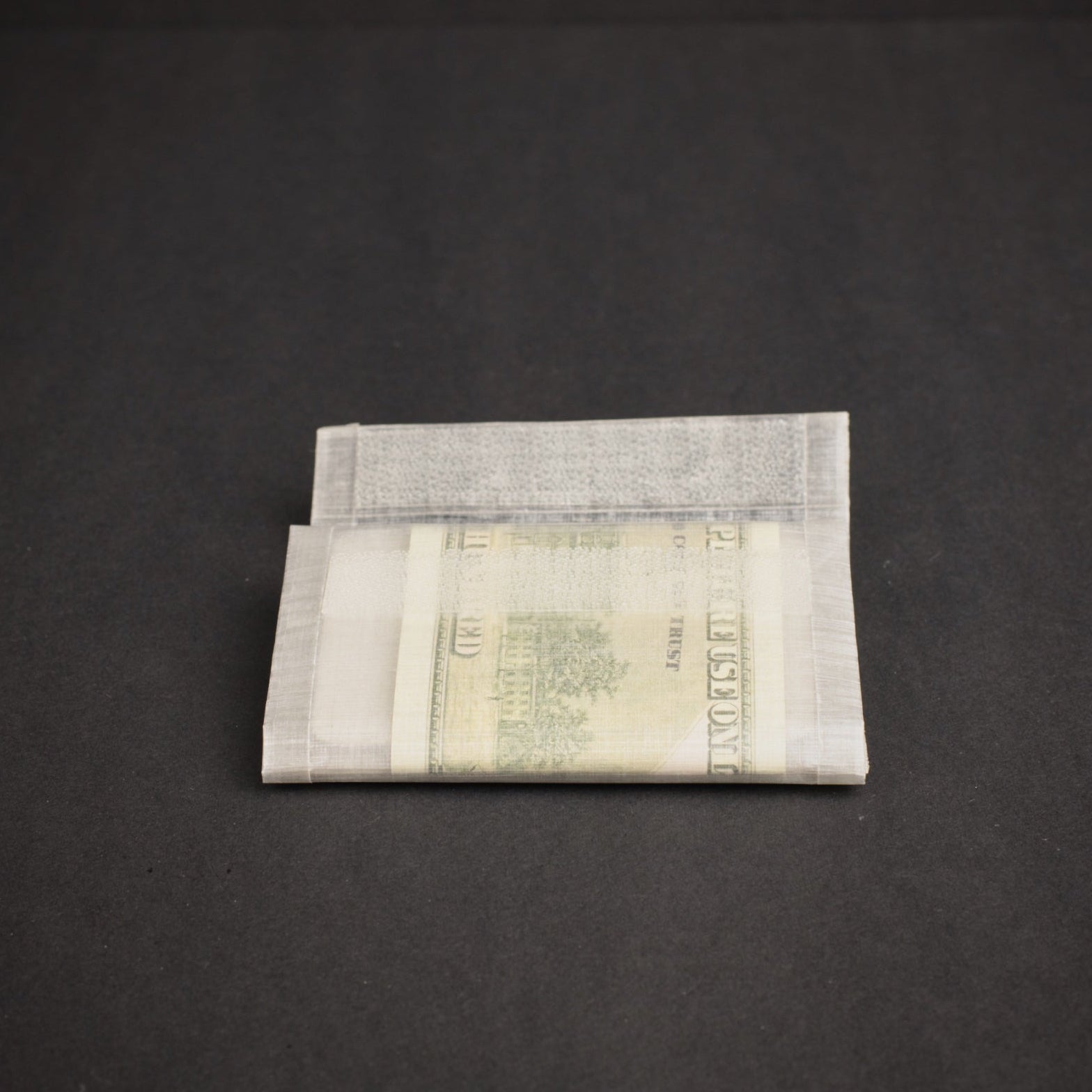 Folded ultralight Dyneema wallet holding cash, showing the slim profile and lightweight bonded construction.