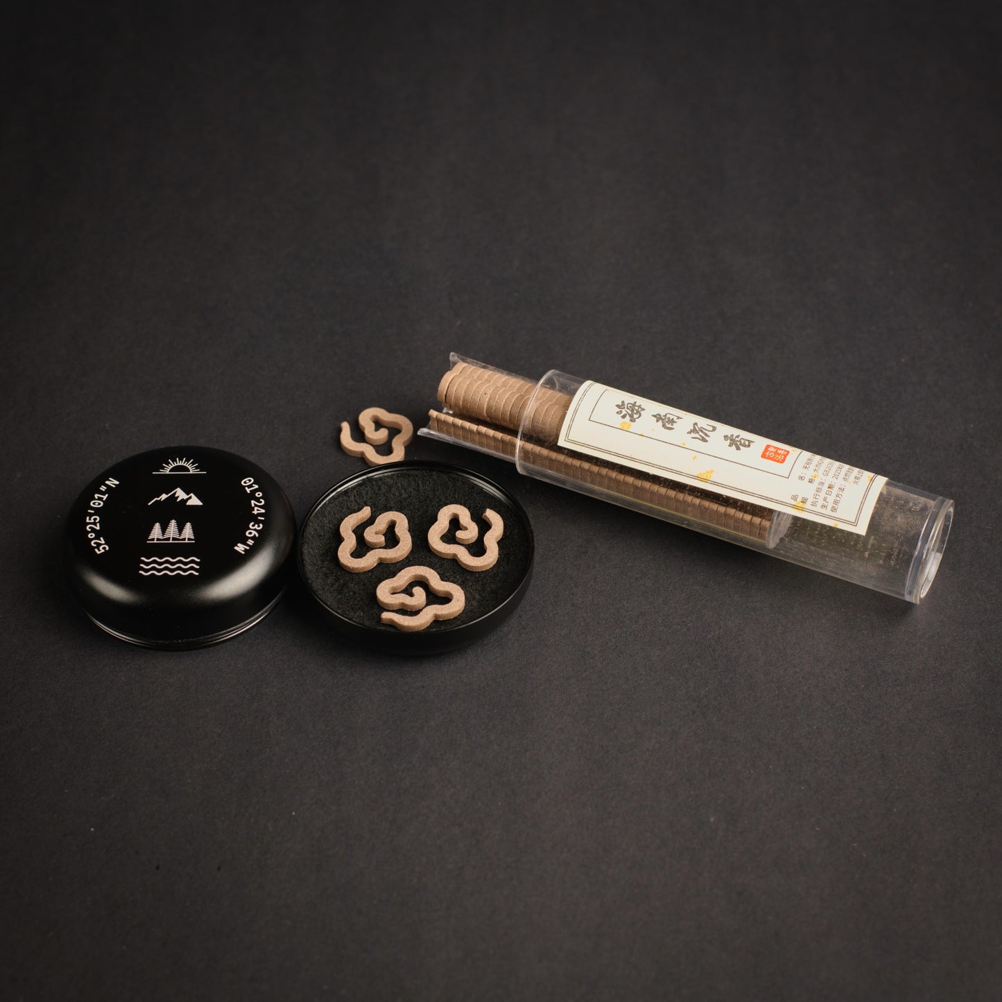 Portable incense burner with engraved coordinates, incense clouds and agarwood incense tube shown on a dark background