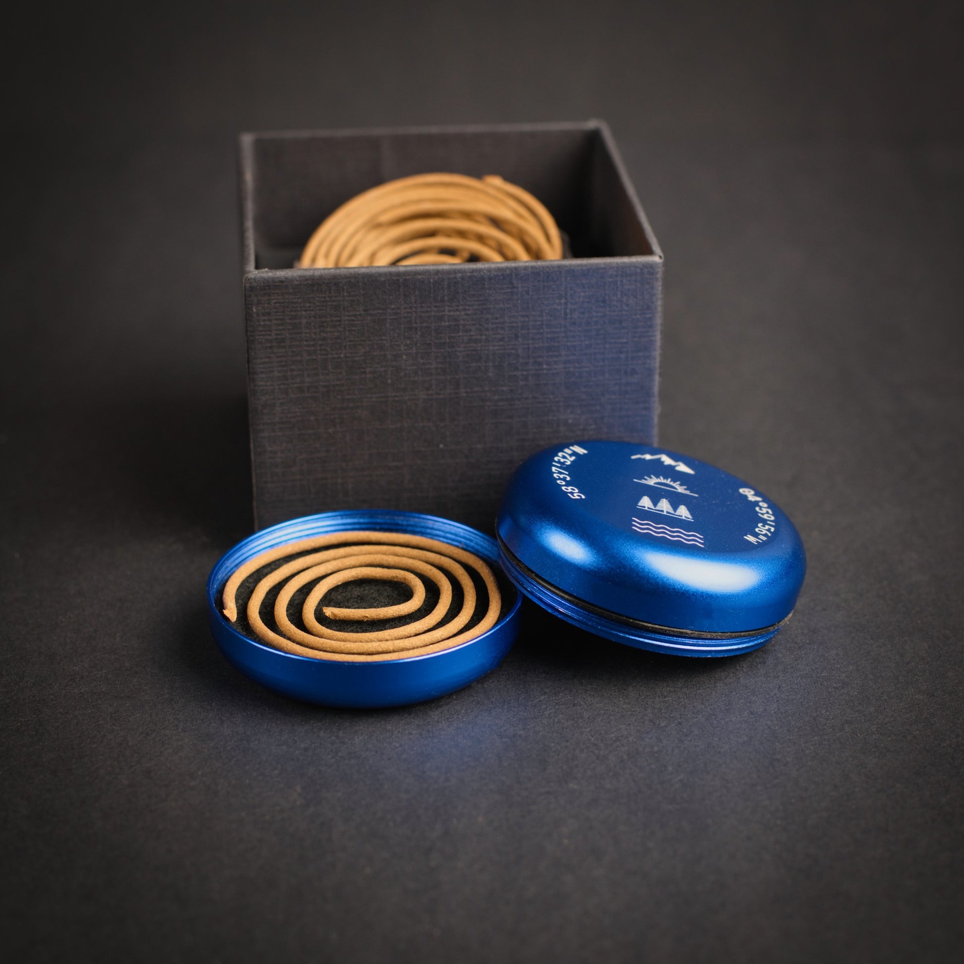 Blue portable incense burner with engraved coordinates and nature-inspired symbols, shown with incense coils and storage box