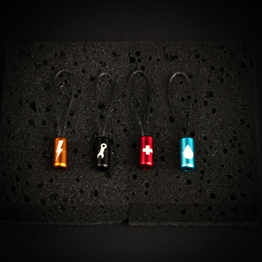 Four ultralight engraved aluminium gear identifier zipper pulls with Dyneema cord loops for power, keys, first aid and water.
