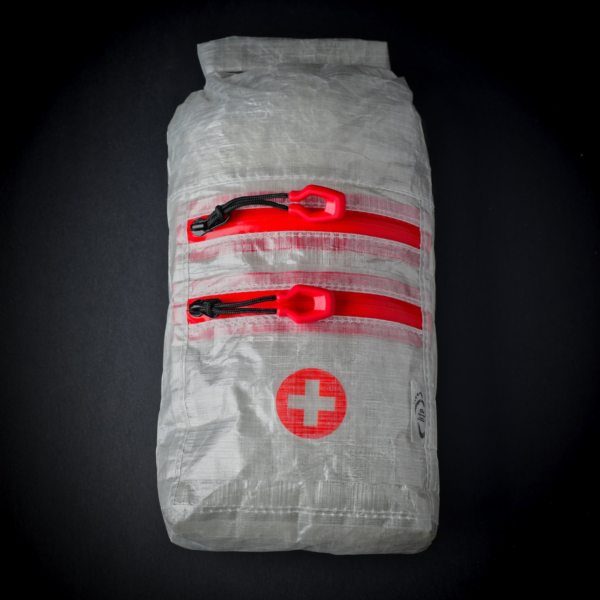 White Dyneema Composite Fabric first aid dry bag with two YKK AquaGuard zip pockets, roll-top closure and first aid cross
