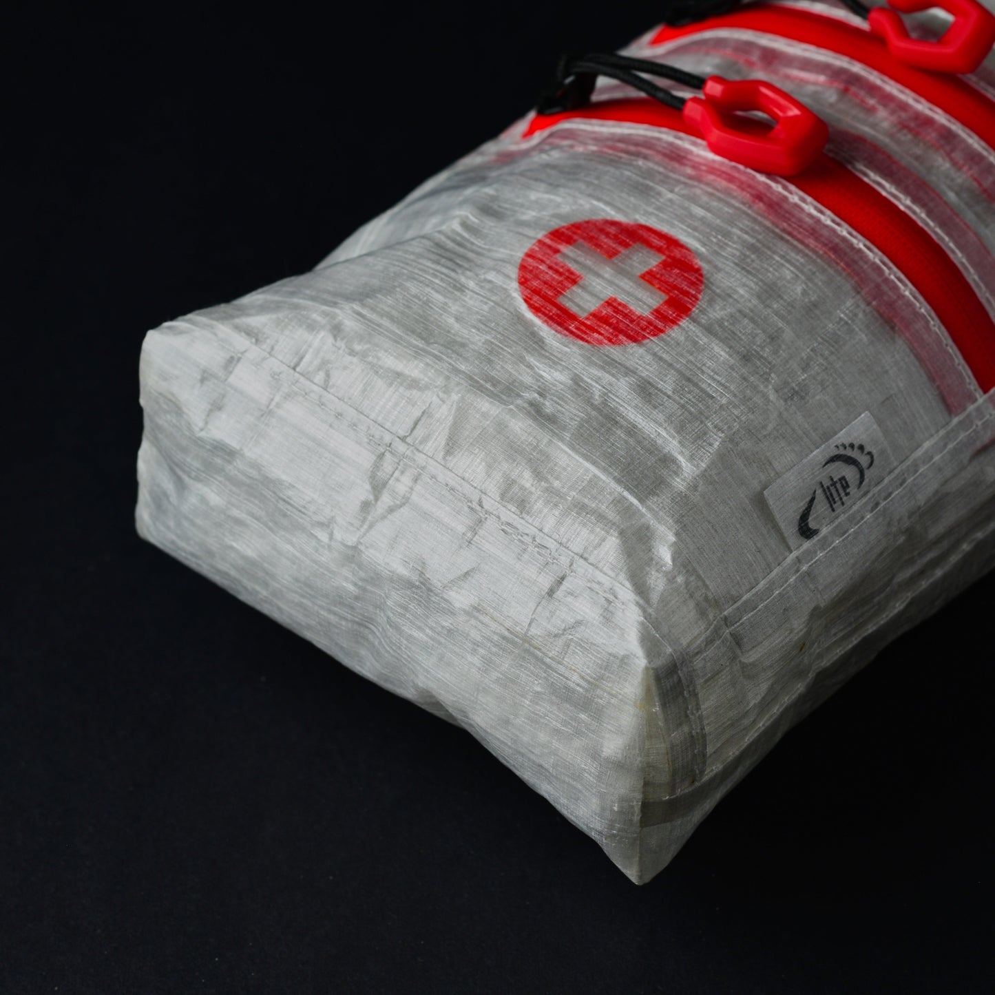 Angled view of lightweight Dyneema first aid dry bag showing twin exterior zip pockets, seam-sealed construction and reinforced base.