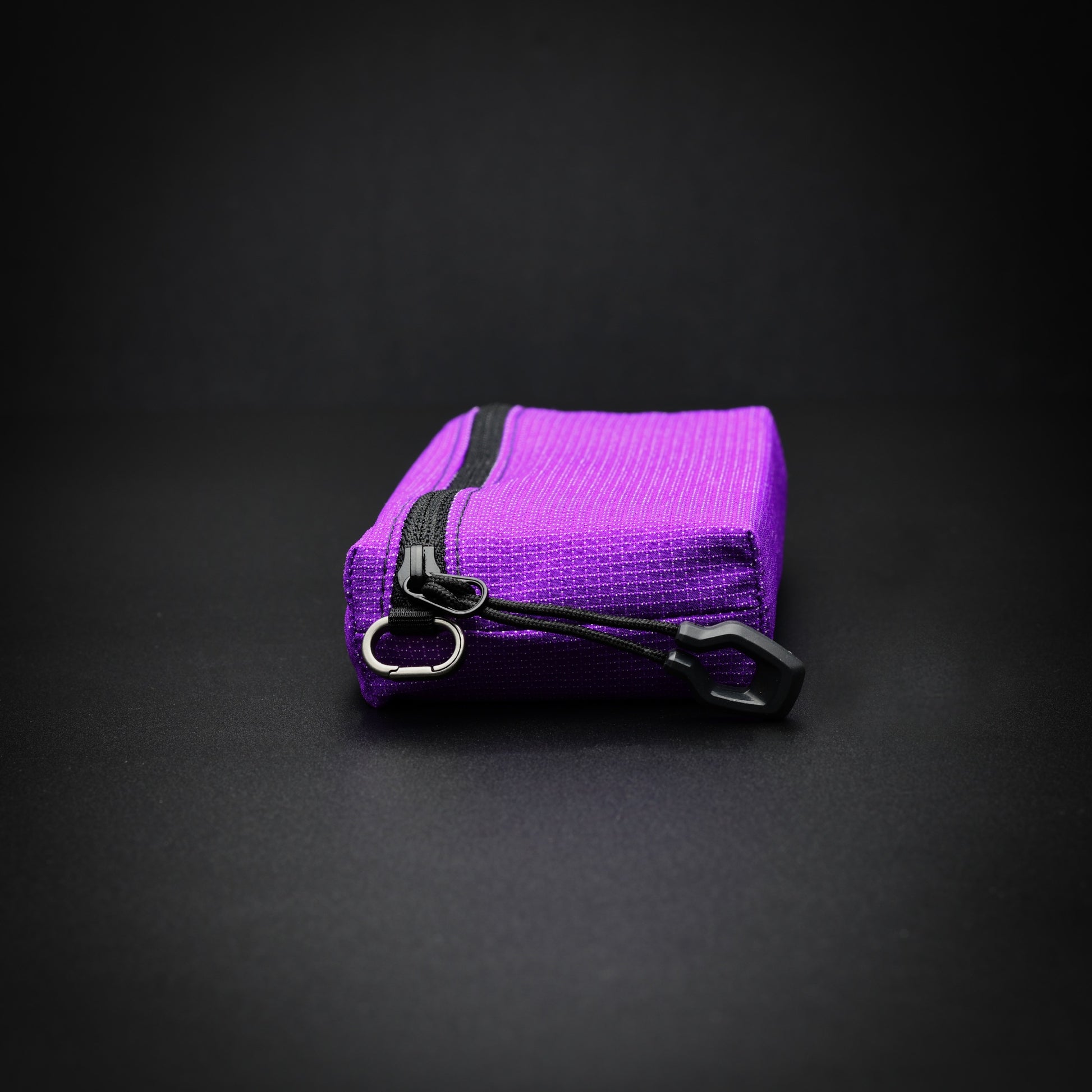 End view of a purple UltraStretch™ expandable accessory case with titanium micro carabiner and glove-compatible zip pull.