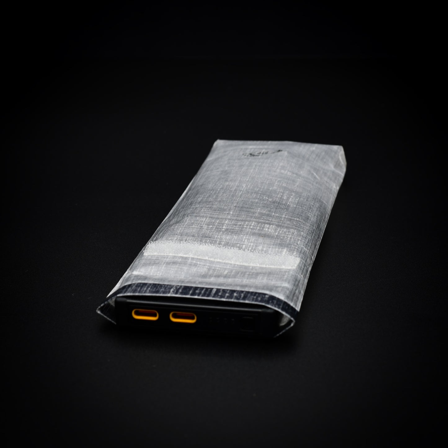 Nitecore NB10000 power bank inside a transparent Dyneema® Composite Fabric dry bag with USB-C ports accessible through the open roll-top.