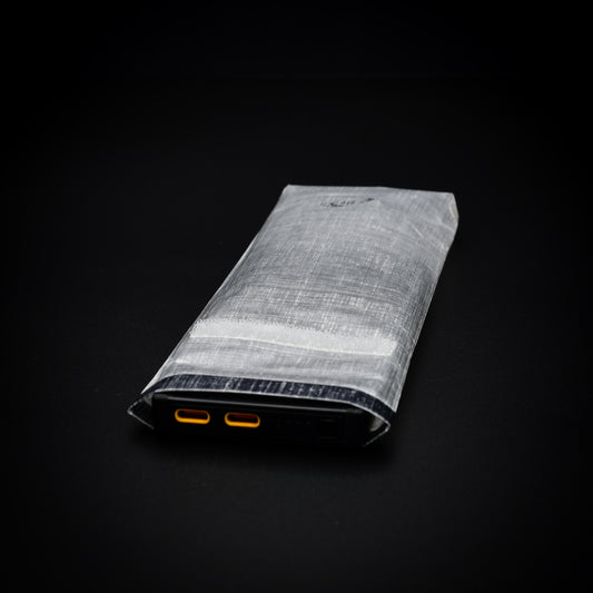 Nitecore NB10000 power bank inside a transparent Dyneema® Composite Fabric dry bag with USB-C ports accessible through the open roll-top.