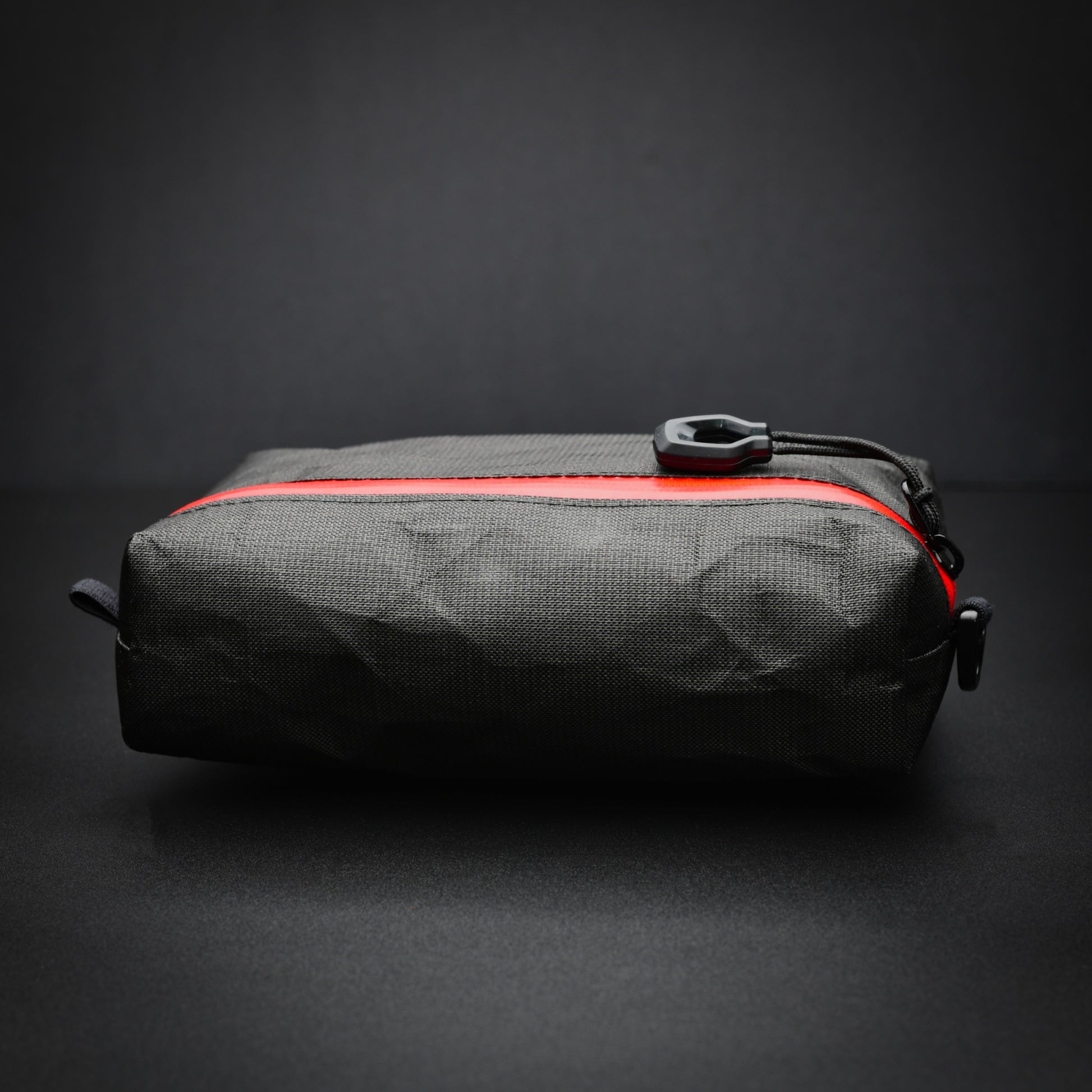 Side profile of a black EcoPak Ultra™ accessory pouch showing the boxed base and red YKK® AquaGuard® zip.