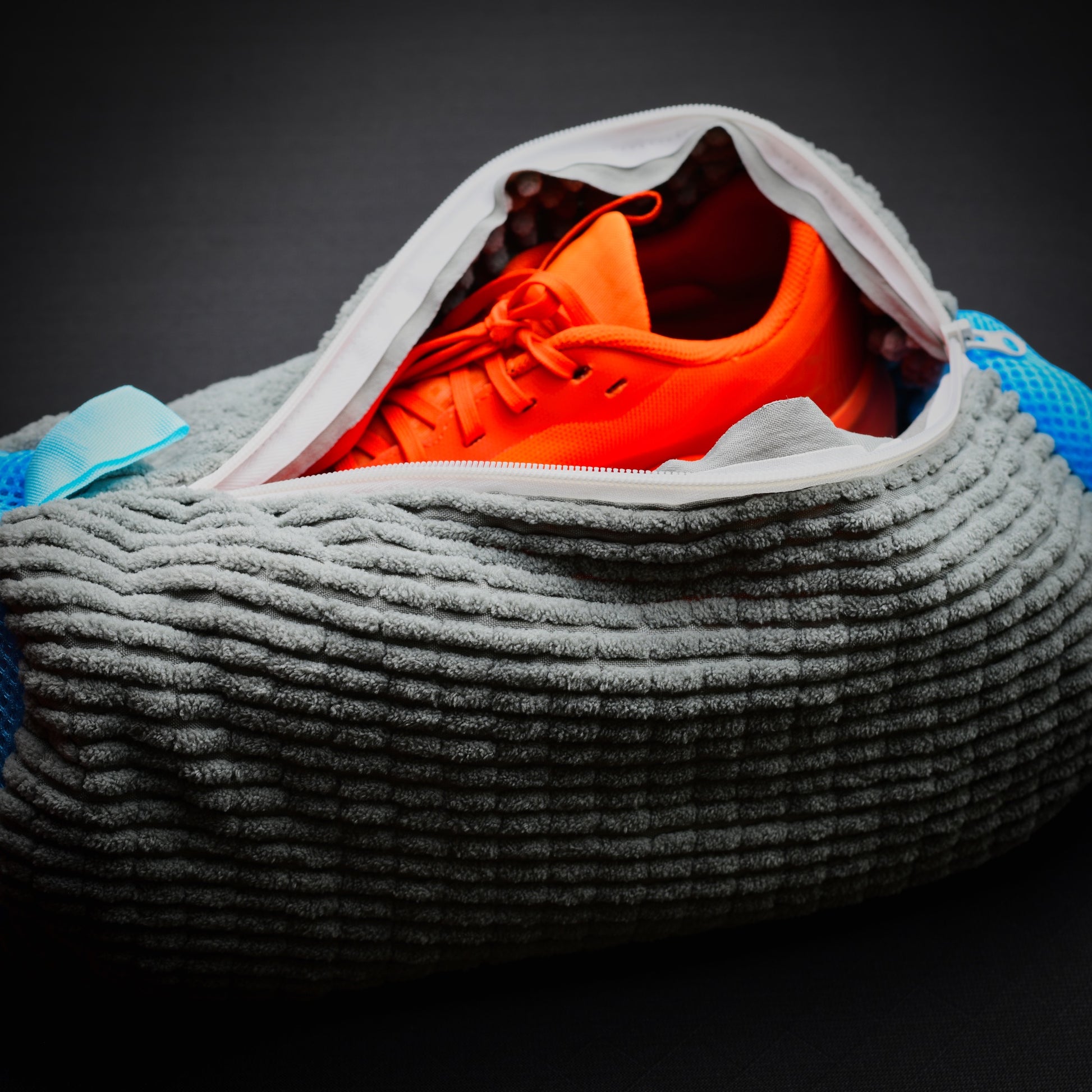 Microfibre trail shoe wash bag with muddy trail running shoe inside, showing full-length zip opening.