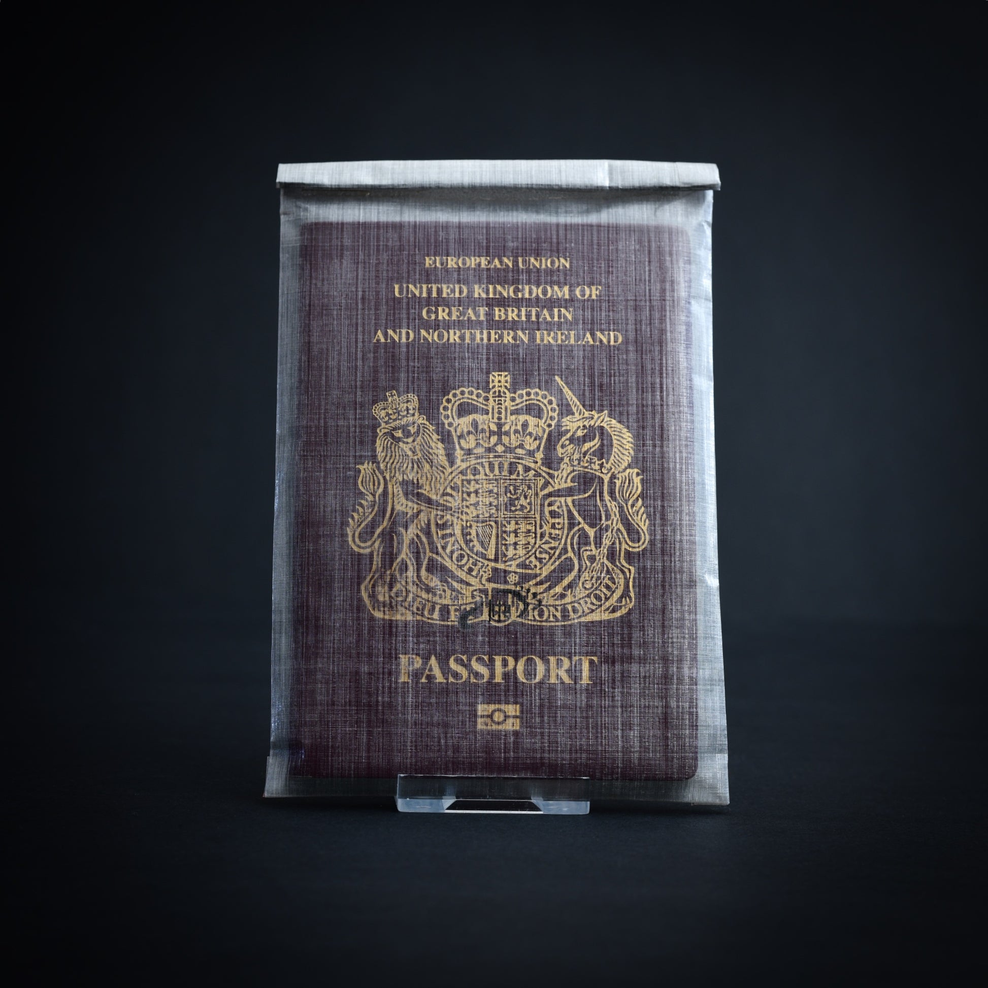 Lightweight bonded Dyneema Composite Fabric roll-top passport sleeve with UK passport inside, offering highly water-resistant travel protection.