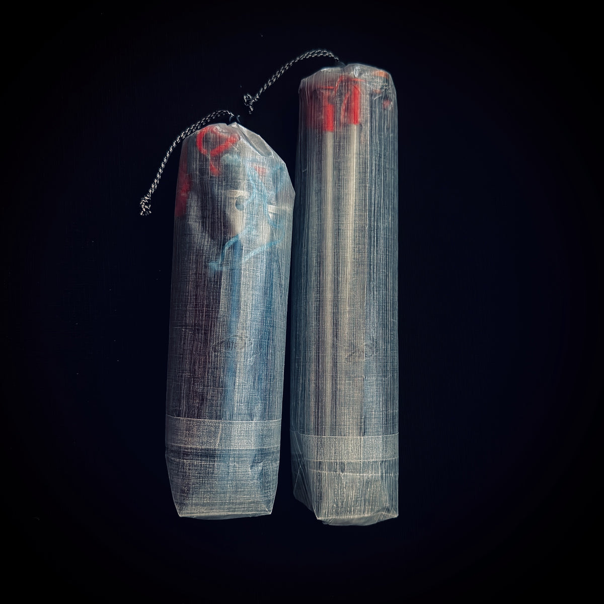 Two translucent Dyneema Composite Fabric tent stake bags standing upright, showing different sizes and drawcord closures.