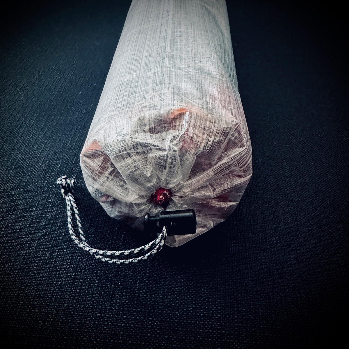 Close-up of the drawcord opening and cord lock on an ultralight translucent DCF tent stake bag.