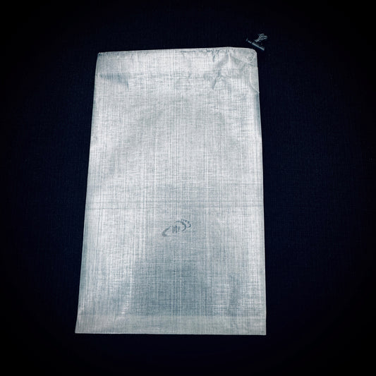 Empty white bonded DCF stuff sack laid flat on a black background
