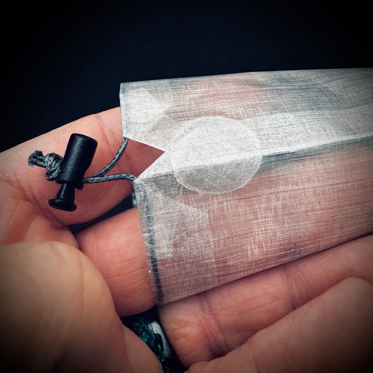 Close-up of the bonded DCF reinforcement patch, Dyneema drawcord and micro cord lock