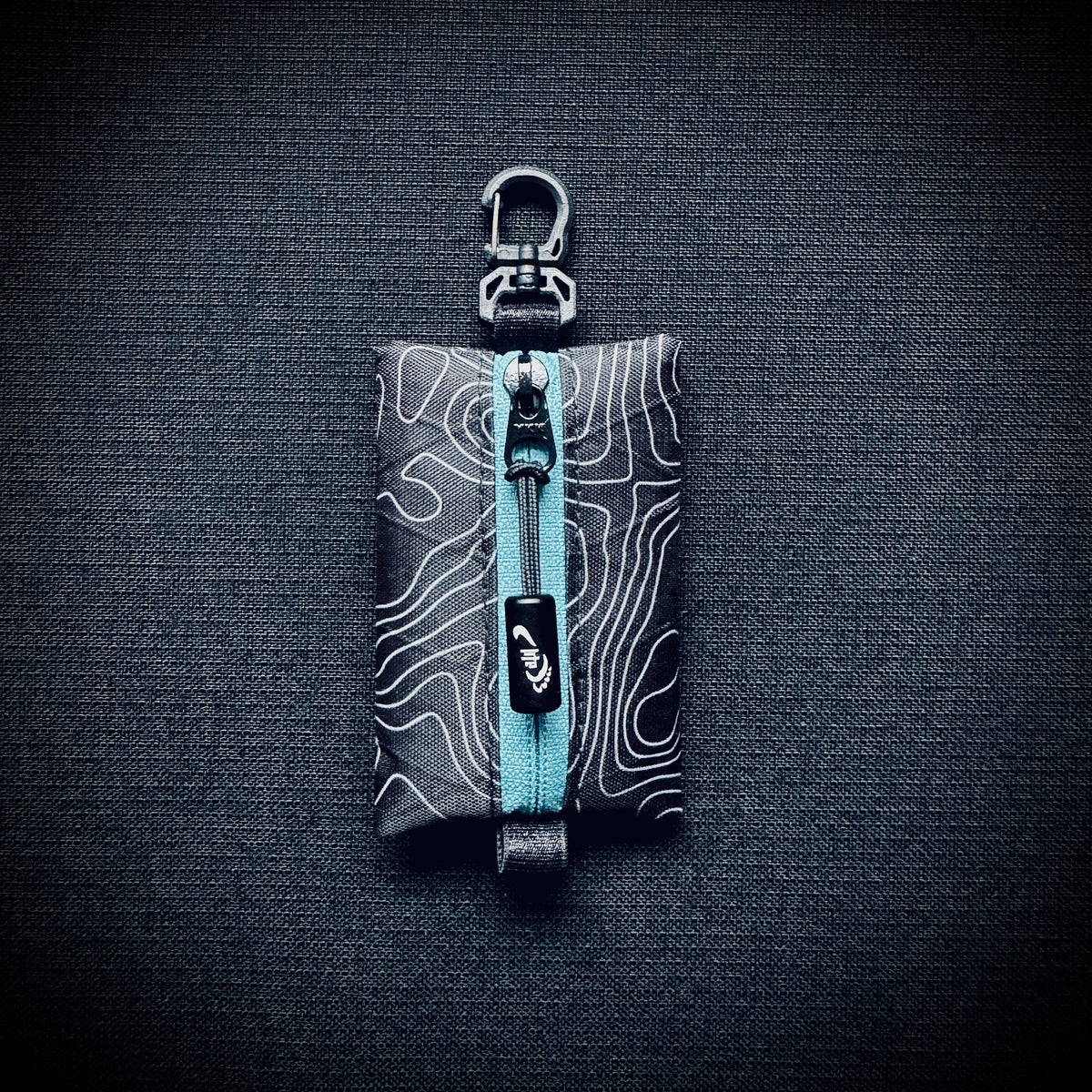 Topo X-Pac micro utility pouch with blue YKK zip, black Dyneema pull cord, engraved Tread Lite aluminium pull and swivel carabiner hook.