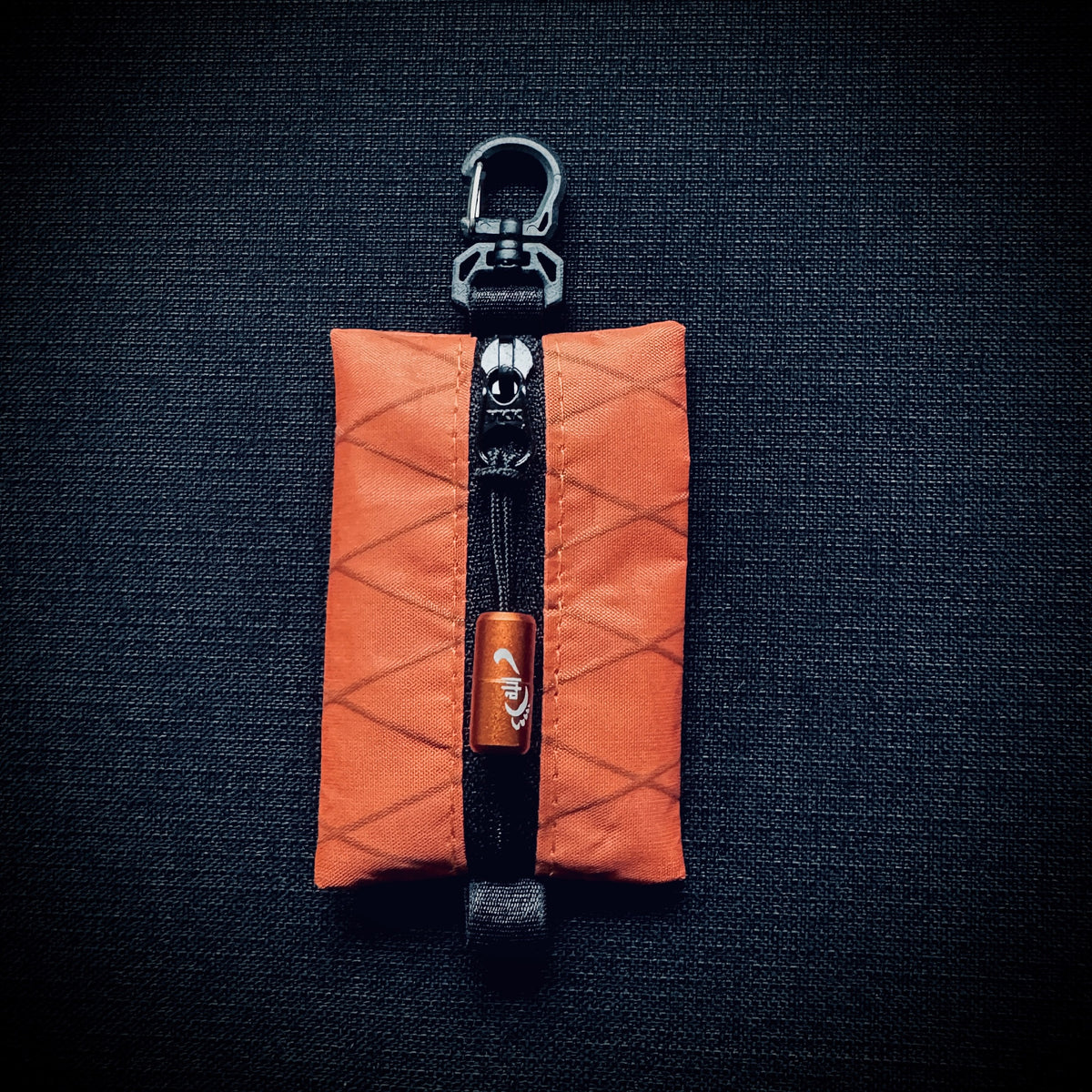 Orange X-Pac VX07 micro utility pouch with black YKK zip, orange engraved Tread Lite pull and swivel carabiner hook.