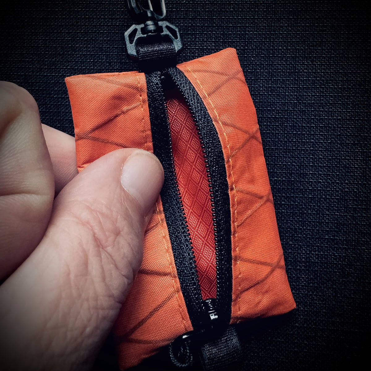 Open orange X-Pac micro utility pouch showing the orange HyperD lining and black YKK reverse-coil zip.