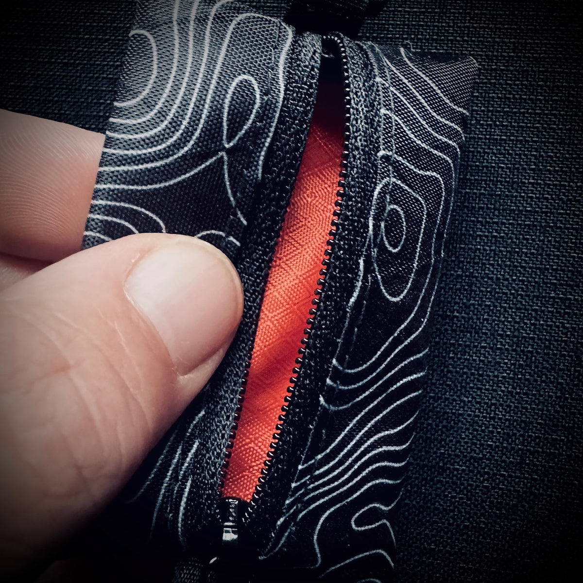 Open black topo X-Pac micro utility pouch showing the orange HyperD lining and bound construction.