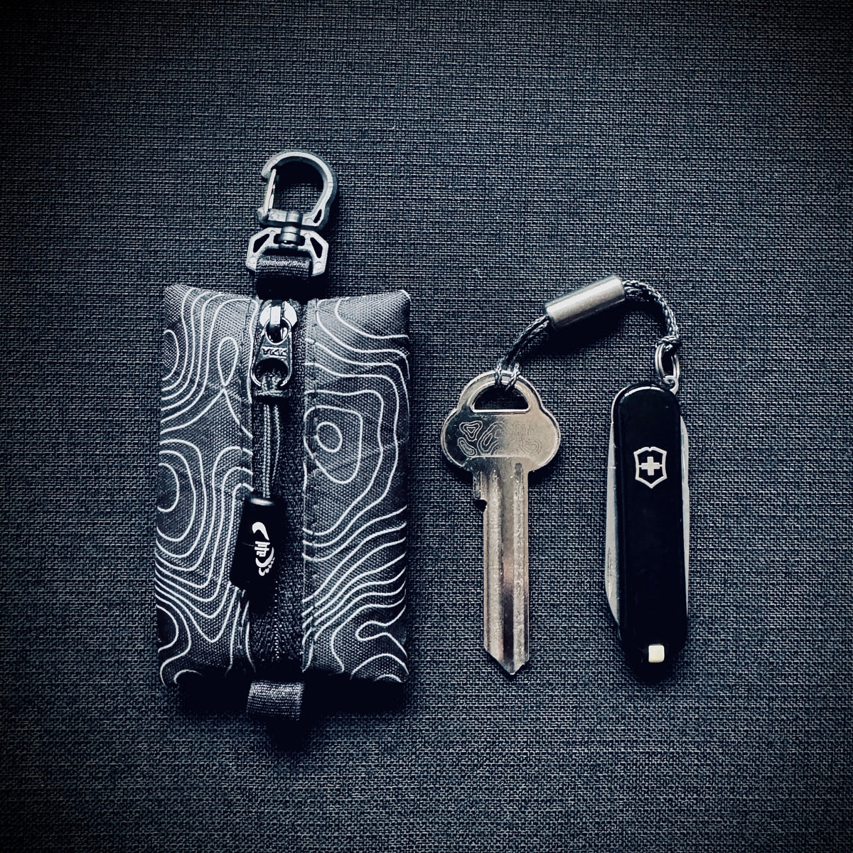 Black topo X-Pac micro utility pouch shown beside a house key and  58mm Victorinox pocket knife for scale.