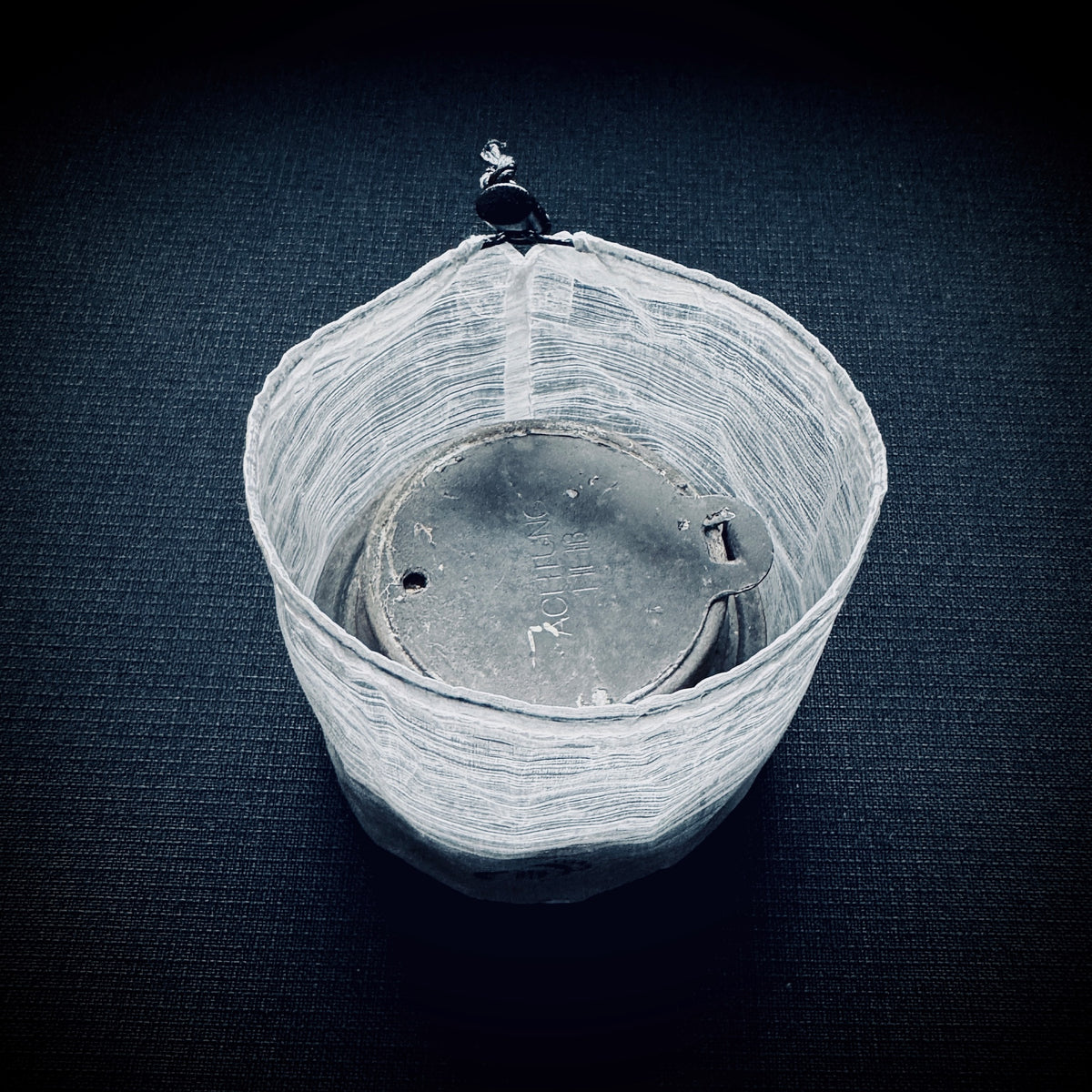 Lightweight white Dyneema stuff sack for a Trangia alcohol burner, shown open with drawcord and micro cord lock.