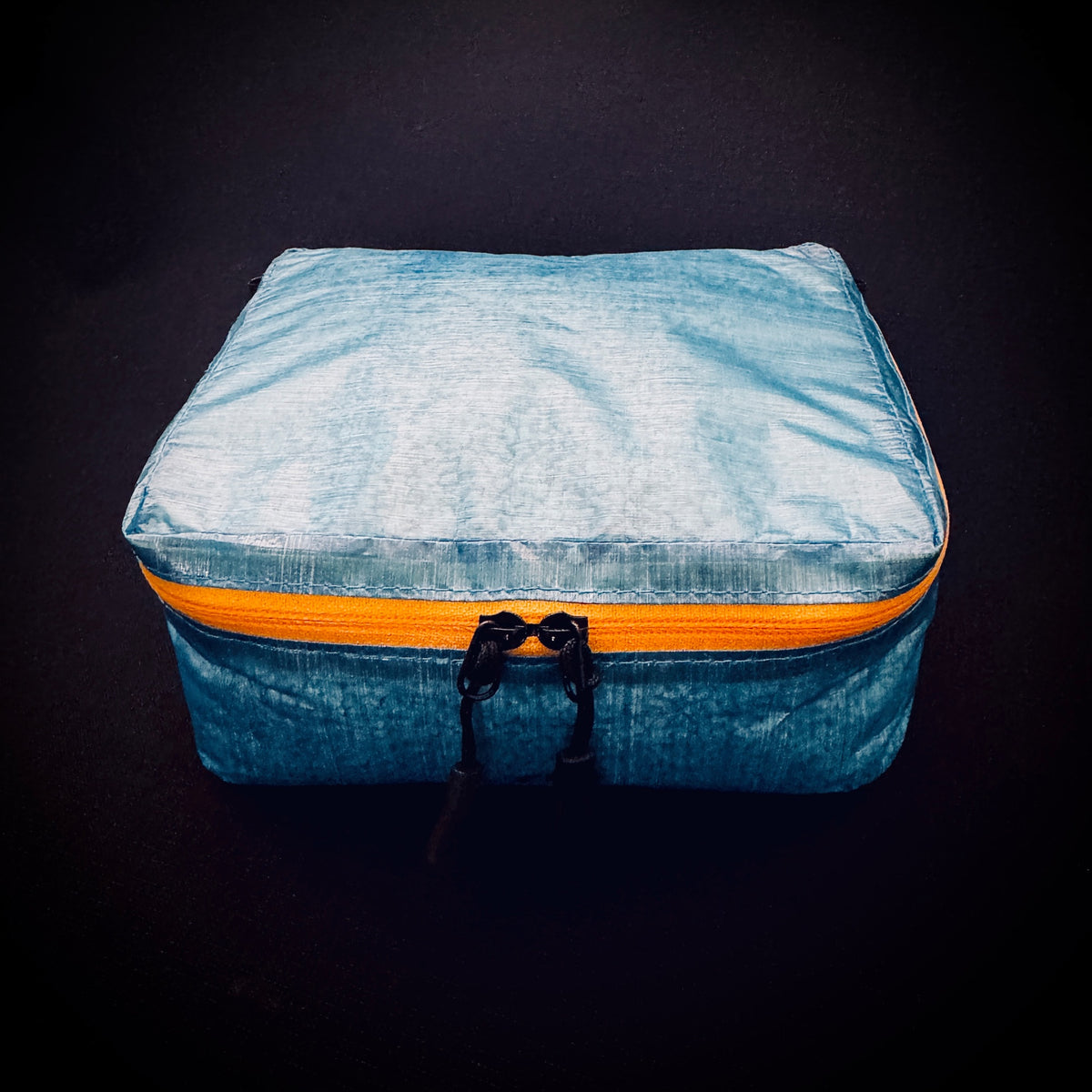 Front view of ultralight blue DCF Mini Packing Cell showing yellow AquaGuard zip and twin black zipper pulls.
