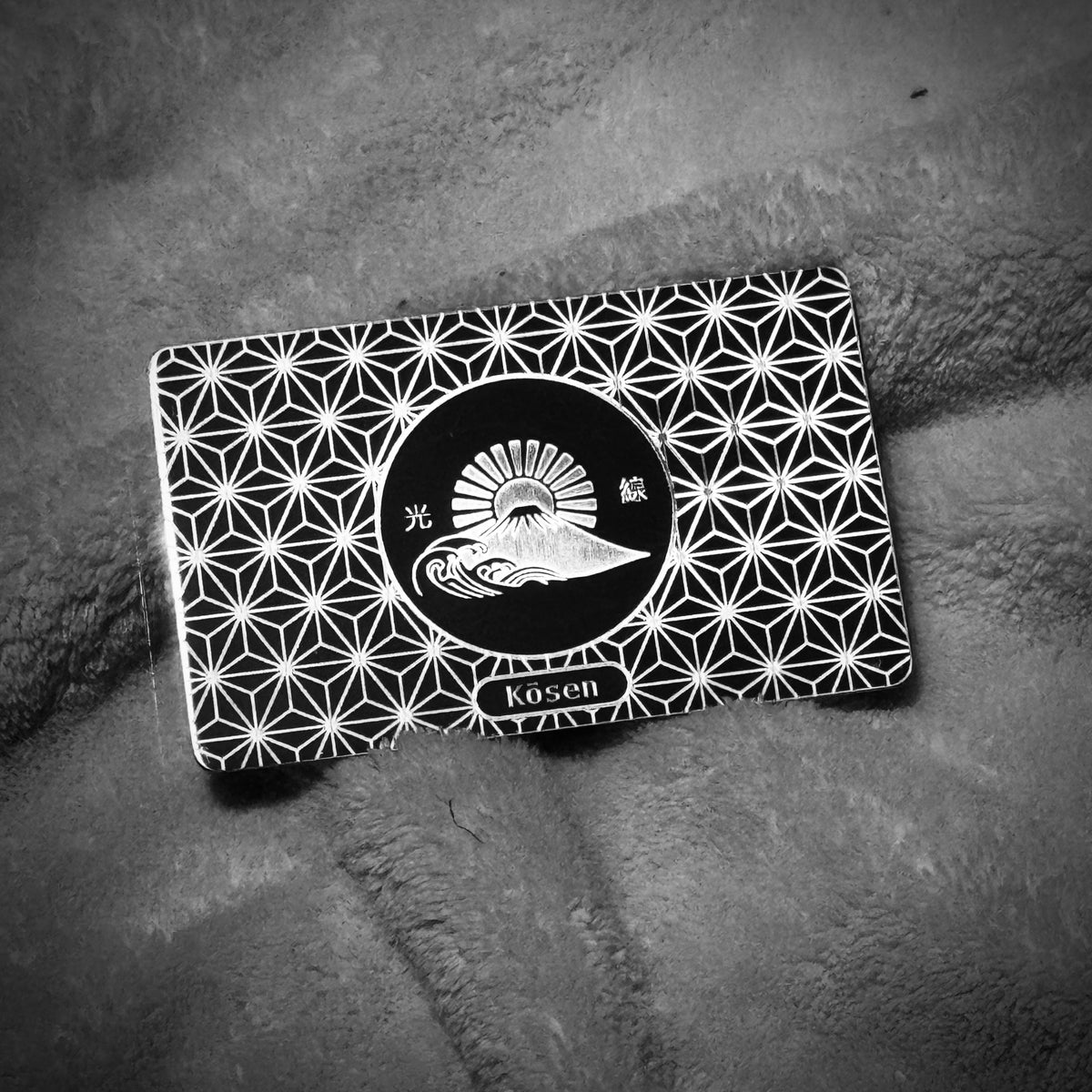 Landscape view of Kōsen Object 001 Inner Strength titanium art card showing silver-on-silver laser oxidation and Asanoha geometry.