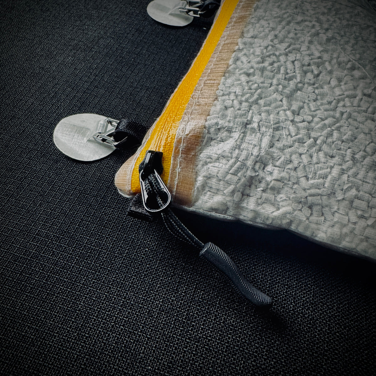 Close-up of the yellow zip, pull and Microdot attachment on the DCF pouch.