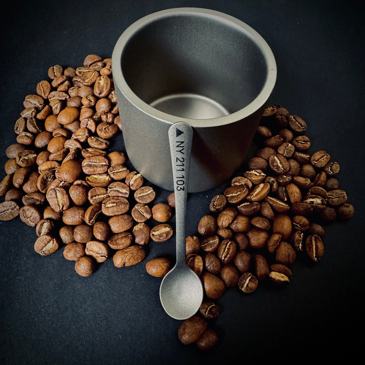 Custom Grade 5 titanium coffee spoon engraved with a Great Gable grid reference, displayed with coffee beans and a titanium cup.