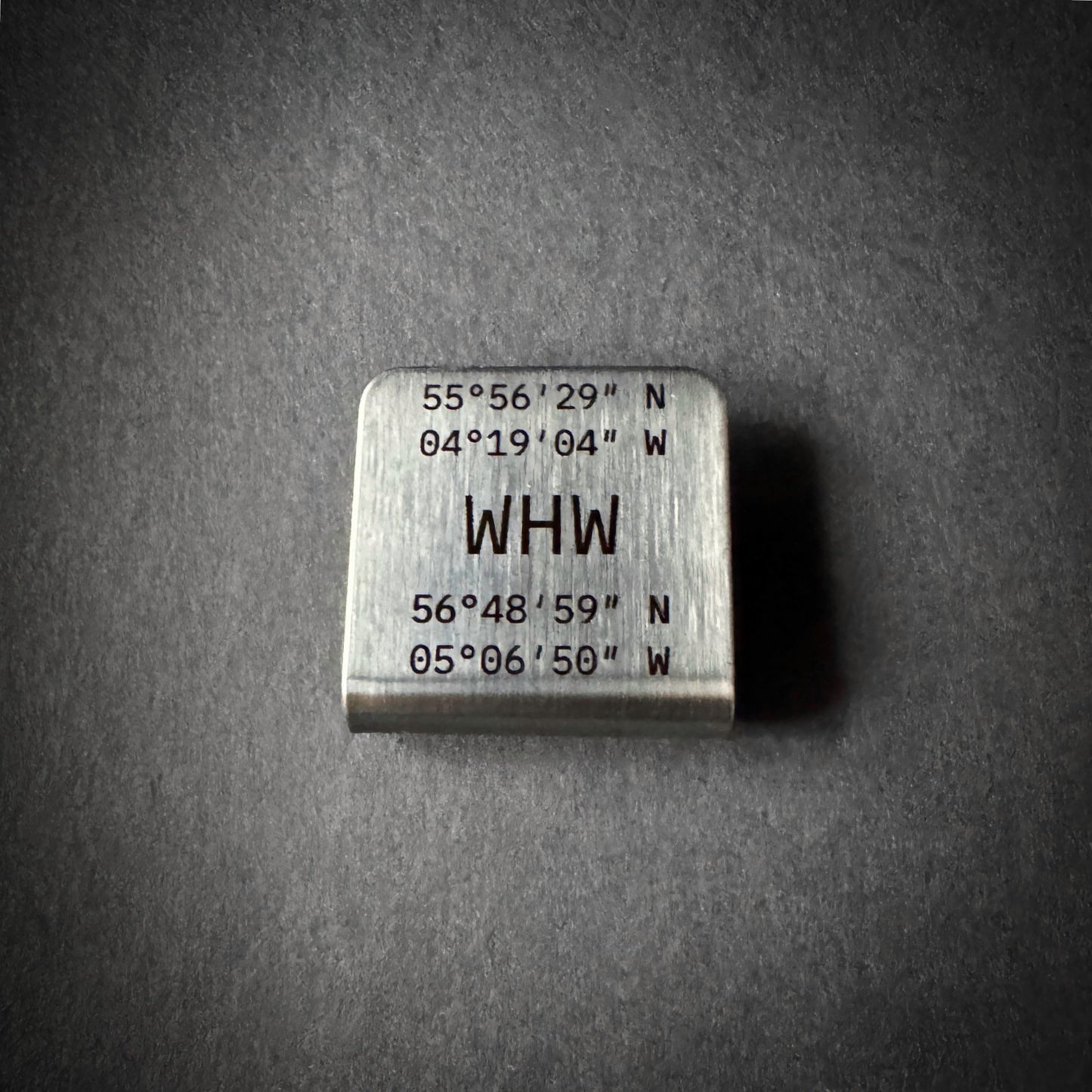 West Highland Way stainless steel hat brim clip engraved with route start and finish coordinates on dark slate background