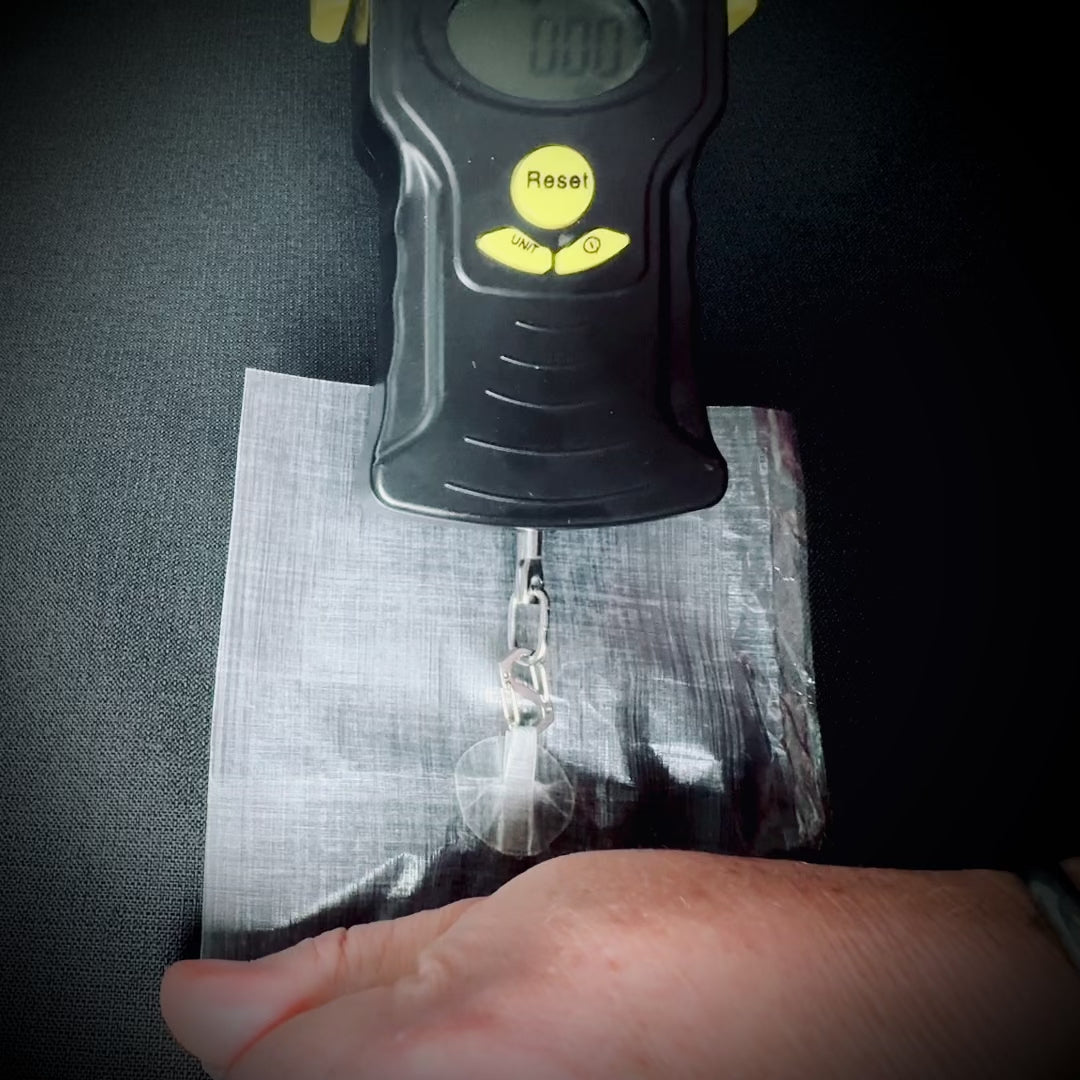 A Microdot adhesive hanging point attached to DCF is pull-tested using a digital scale.